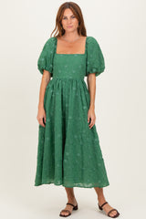 woman wearing a green puff sleeve midi dress with a square neckline and floral embroidery