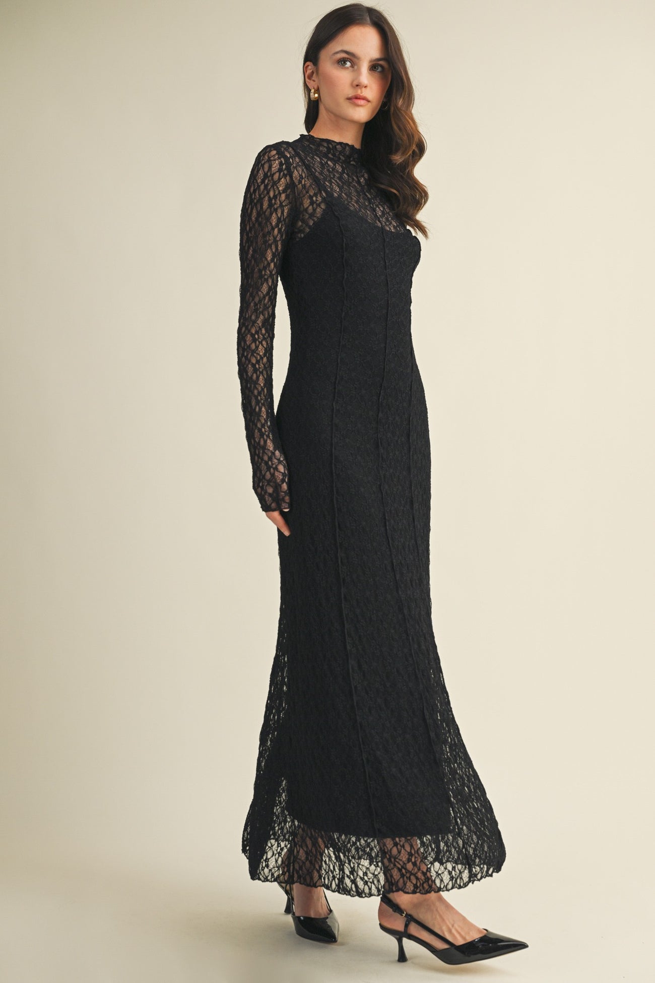 woman wearing a black lace long sleeve evening gown with a fitted silhouette and a sheer neckline