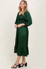 woman wearing a green smocked midi dress with puff sleeves and a ruffled hem, styled with black strappy heels