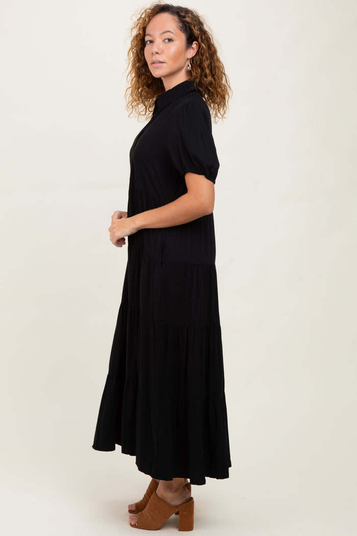 woman wearing a black tiered maxi dress with short sleeves and a collar