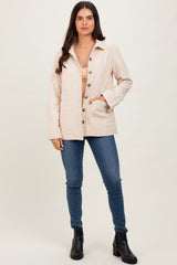 woman wearing a light beige quilted button-up jacket, paired with a nude top and blue skinny jeans, black ankle boots