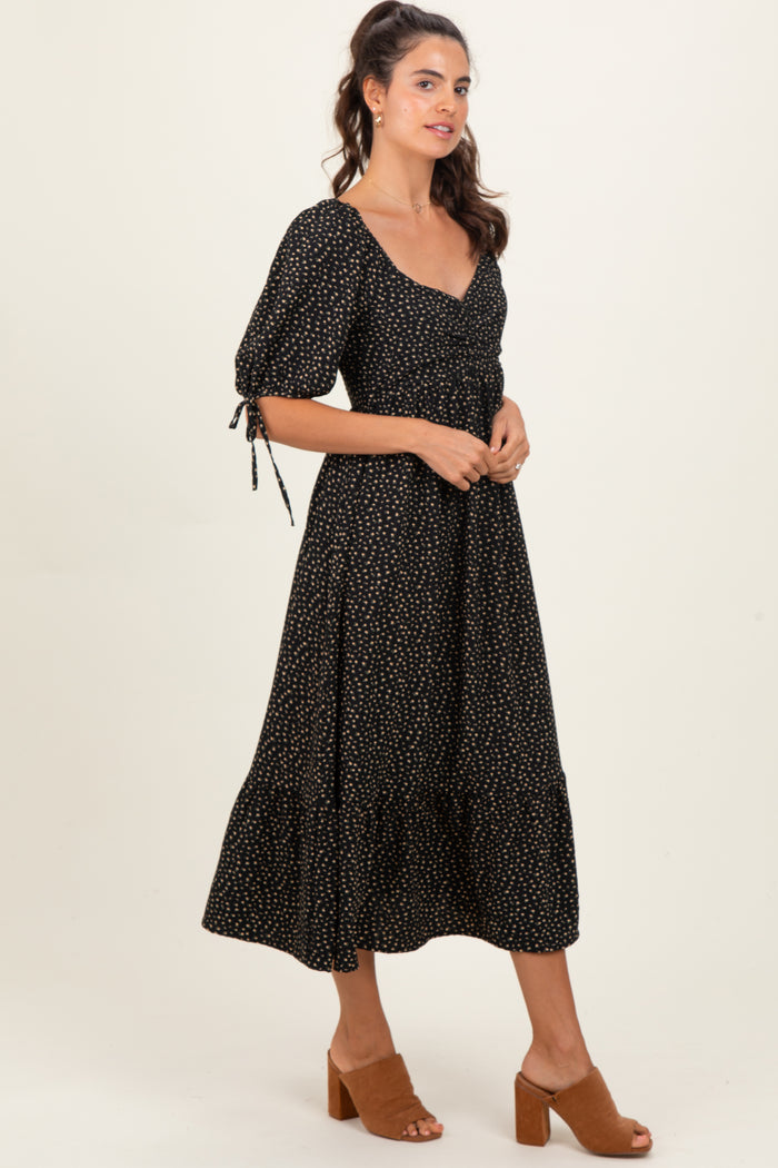 woman wearing a black midi dress with puff sleeves and gold polka dots, styled with brown heeled sandals