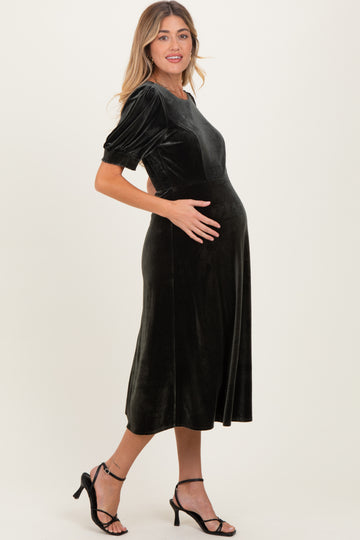 woman wearing a black velvet maternity dress with short puff sleeves and a visible baby bump