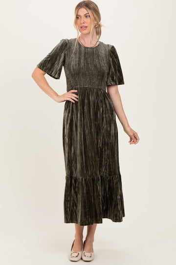 woman wearing a dark green velvet maxi dress with short sleeves and a tiered skirt