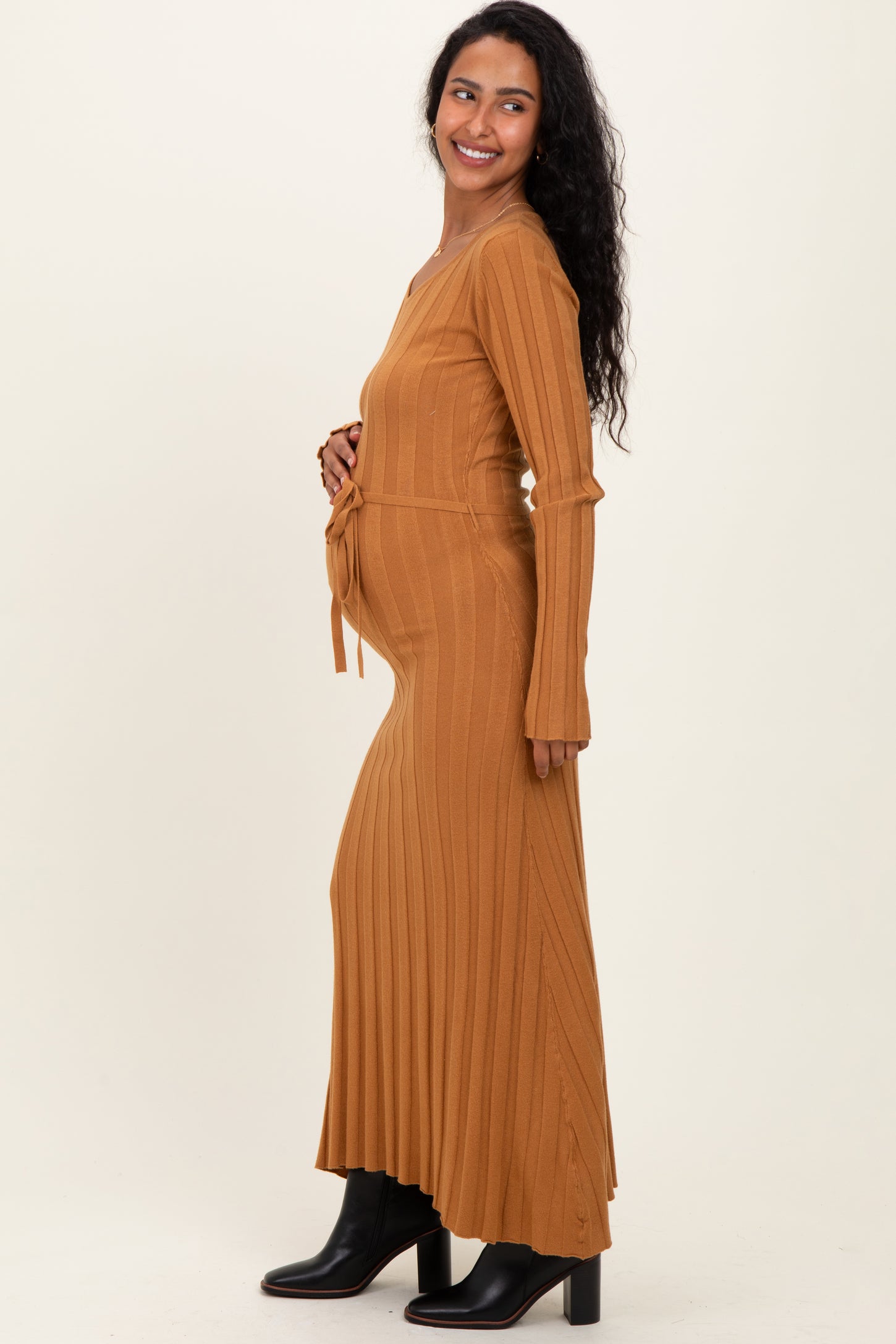 woman wearing a ribbed mustard long sleeve maternity dress, styled with a tie at the waist and showing her baby bump