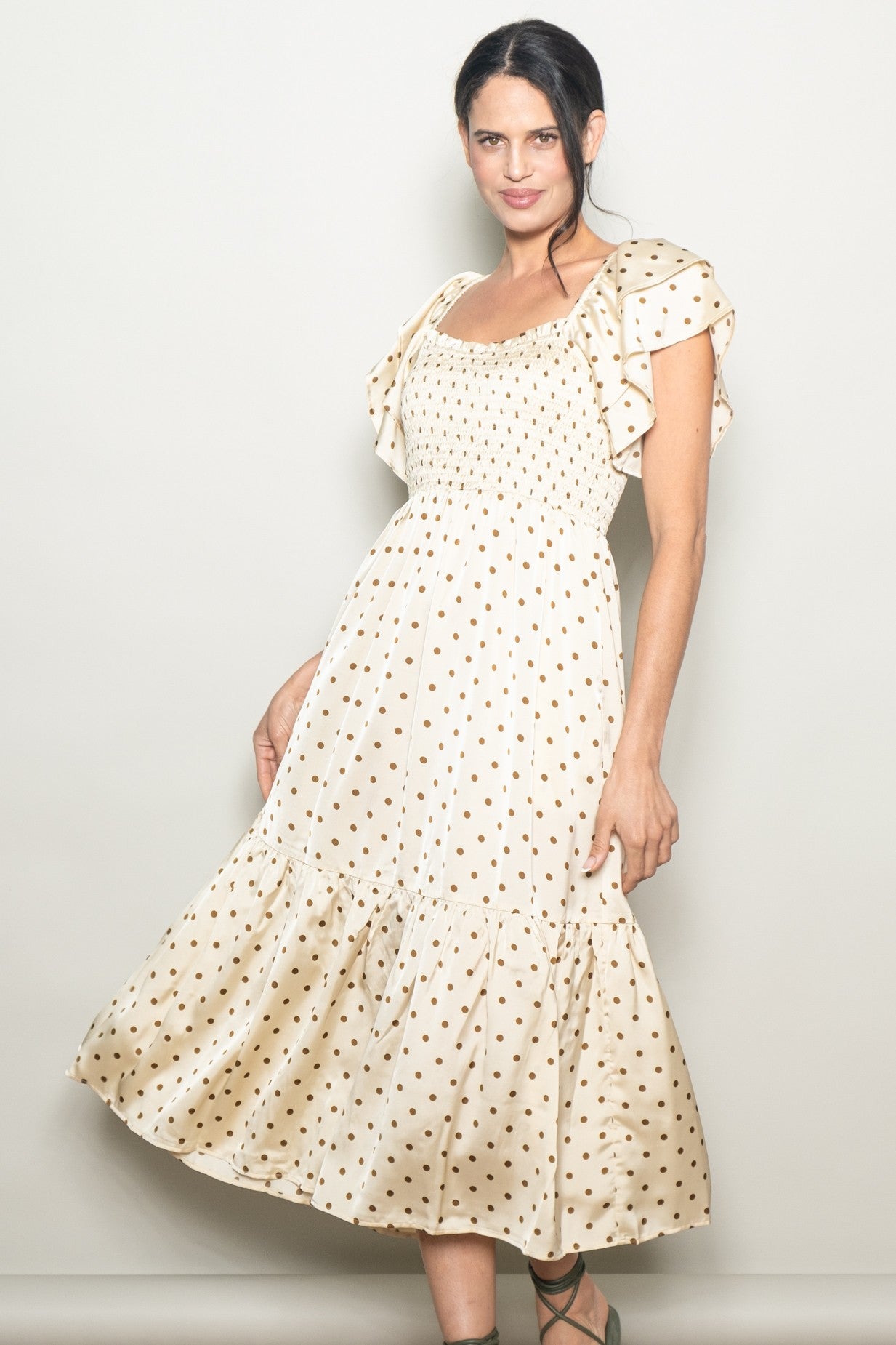 woman wearing a cream polka dot midi dress with ruffled sleeves and a smocked bodice