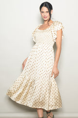 woman wearing a cream polka dot midi dress with ruffled sleeves and a smocked bodice