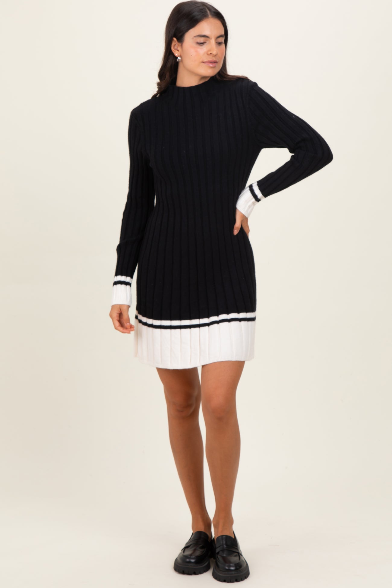 woman wearing a black ribbed sweater dress with white stripe details and long sleeves