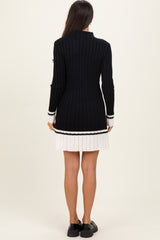 woman wearing a black ribbed long cardigan with white stripe details, standing with her back to the camera
