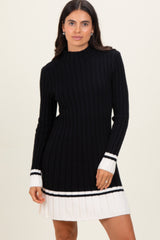 woman wearing a black ribbed knit dress with white pleated hem and striped sleeves