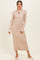woman wearing a long beige ribbed knit dress with a tie neck and white trim on the sleeves