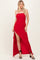 woman wearing a red strapless maxi dress with a high slit and fitted silhouette, posing with one hand on her hip