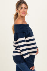 woman wearing a navy blue and white striped off-the-shoulder maternity sweater and holding her baby bump