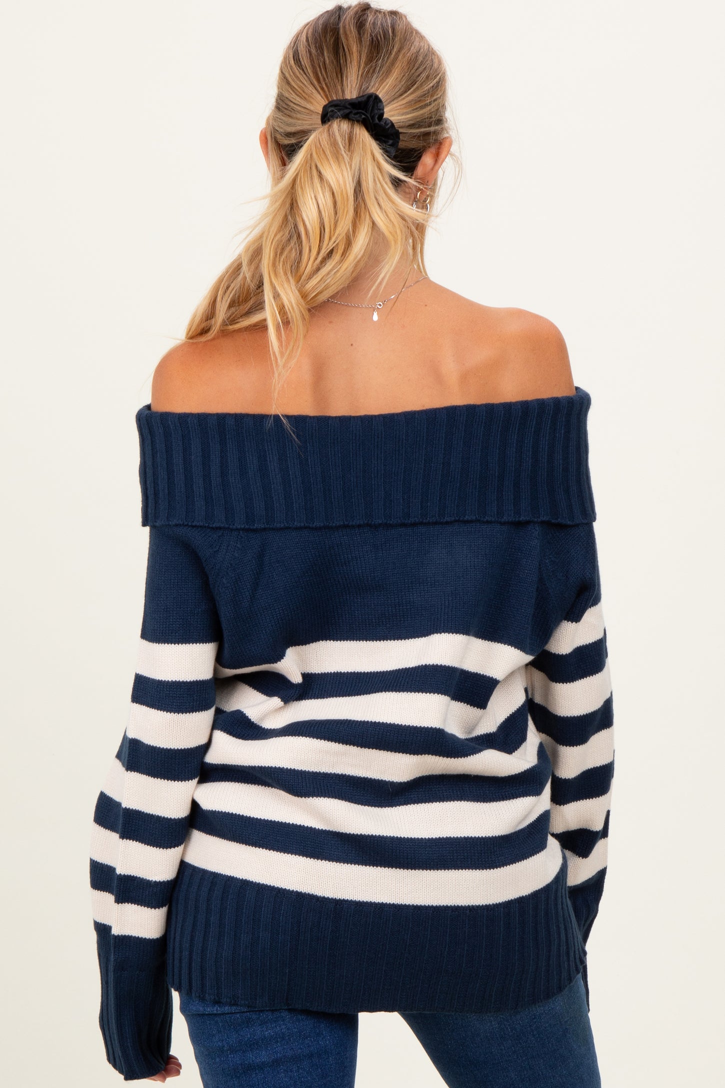 woman wearing a navy and white striped off-the-shoulder maternity sweater from the back with long sleeves