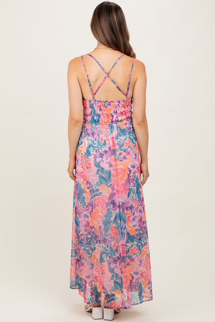 woman wearing a colorful floral maternity maxi dress with adjustable crisscross straps and a smocked back