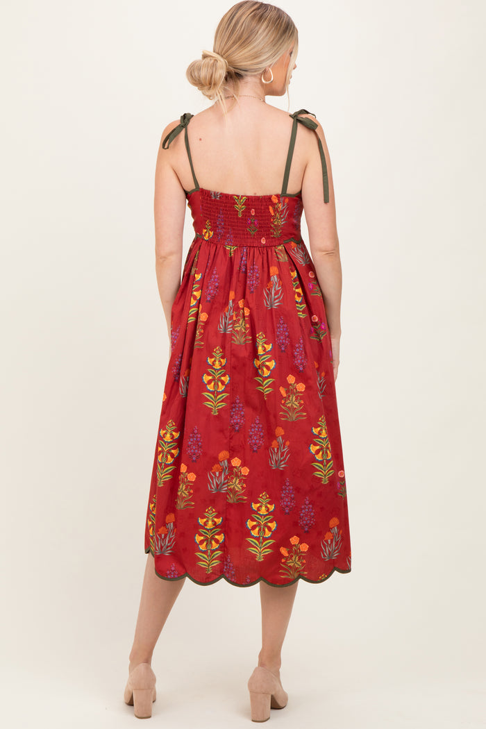 woman wearing a red midi dress with floral print and tie straps, showing a smocked back detail