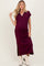 woman wearing a burgundy maternity maxi dress with a v-neck and white trim details, showing her baby bump