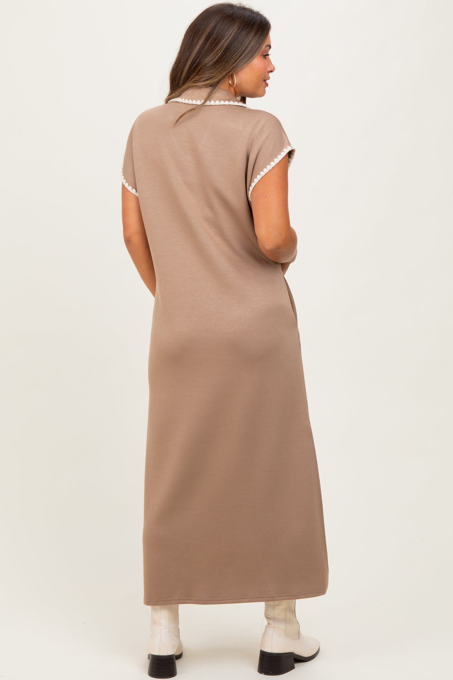 woman wearing a brown maternity maxi dress with short sleeves and decorative trim, showing a side view with no baby bump visible