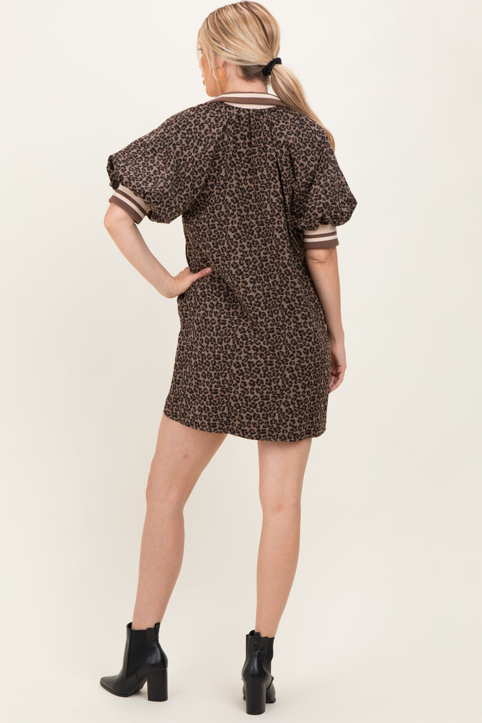 woman wearing a brown leopard print short dress with puff sleeves and stripe details, standing with her back to the camera