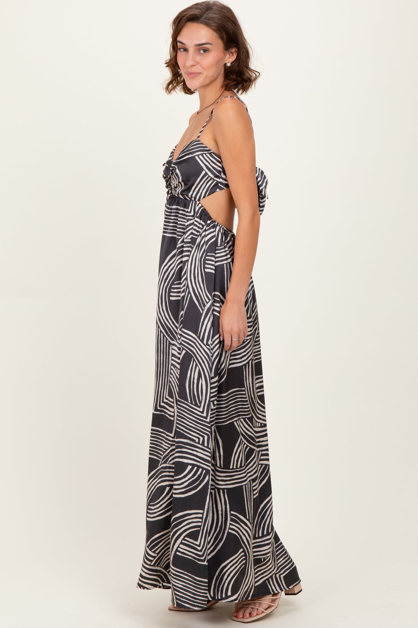 woman wearing a black and white patterned maxi dress with cut-out details and a tie at the back