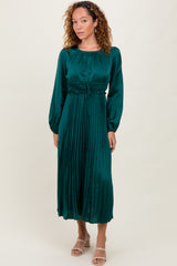 woman wearing a dark green midi dress with pleated skirt and long sleeves, styled with open-toe heels
