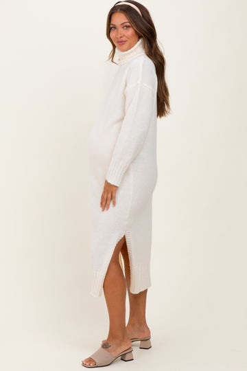 woman wearing a cream maternity sweater dress with side slits, showcasing her baby bump
