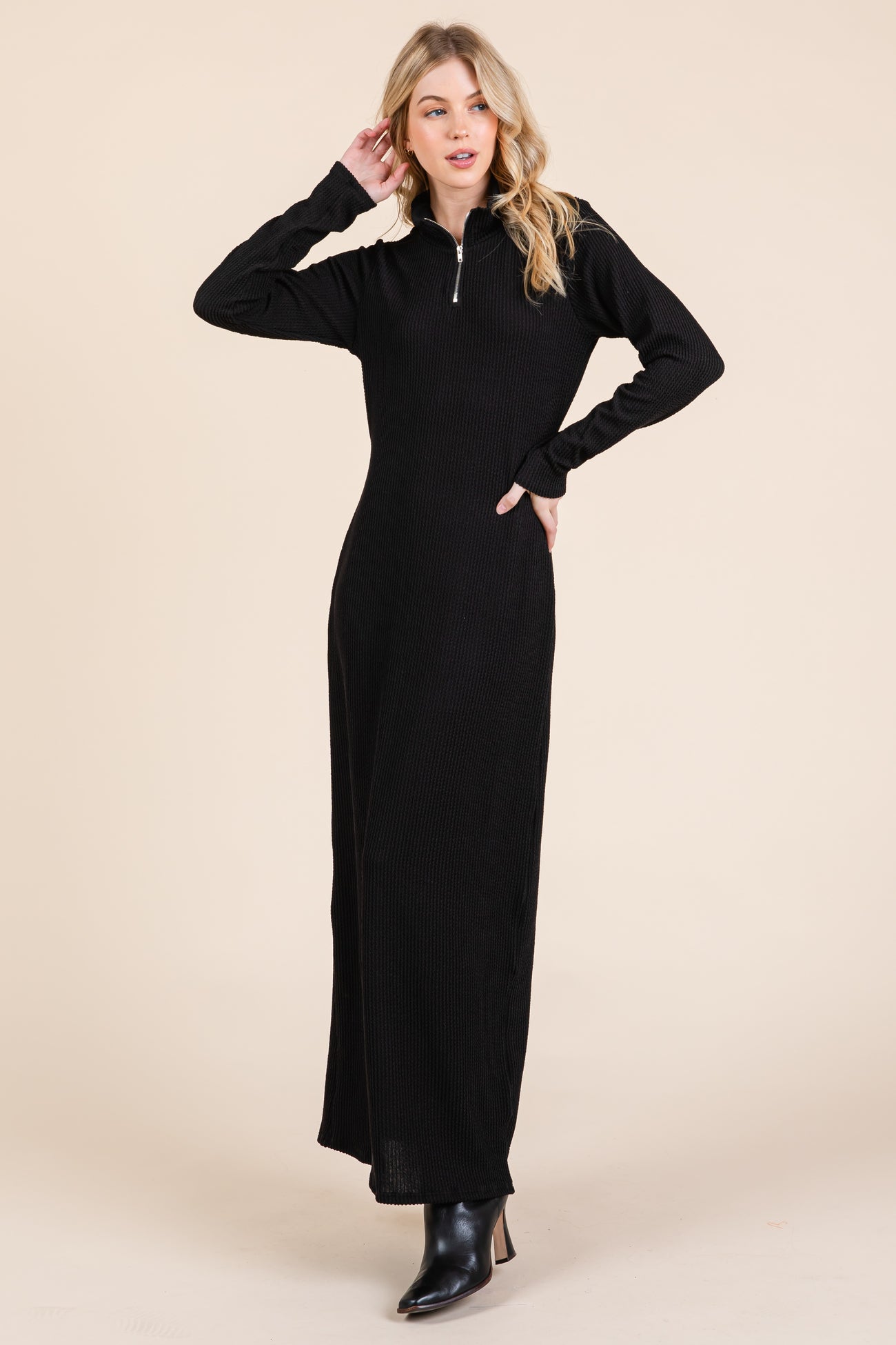 woman wearing a black long sleeve zip-up maxi dress with a textured fabric and ankle boots