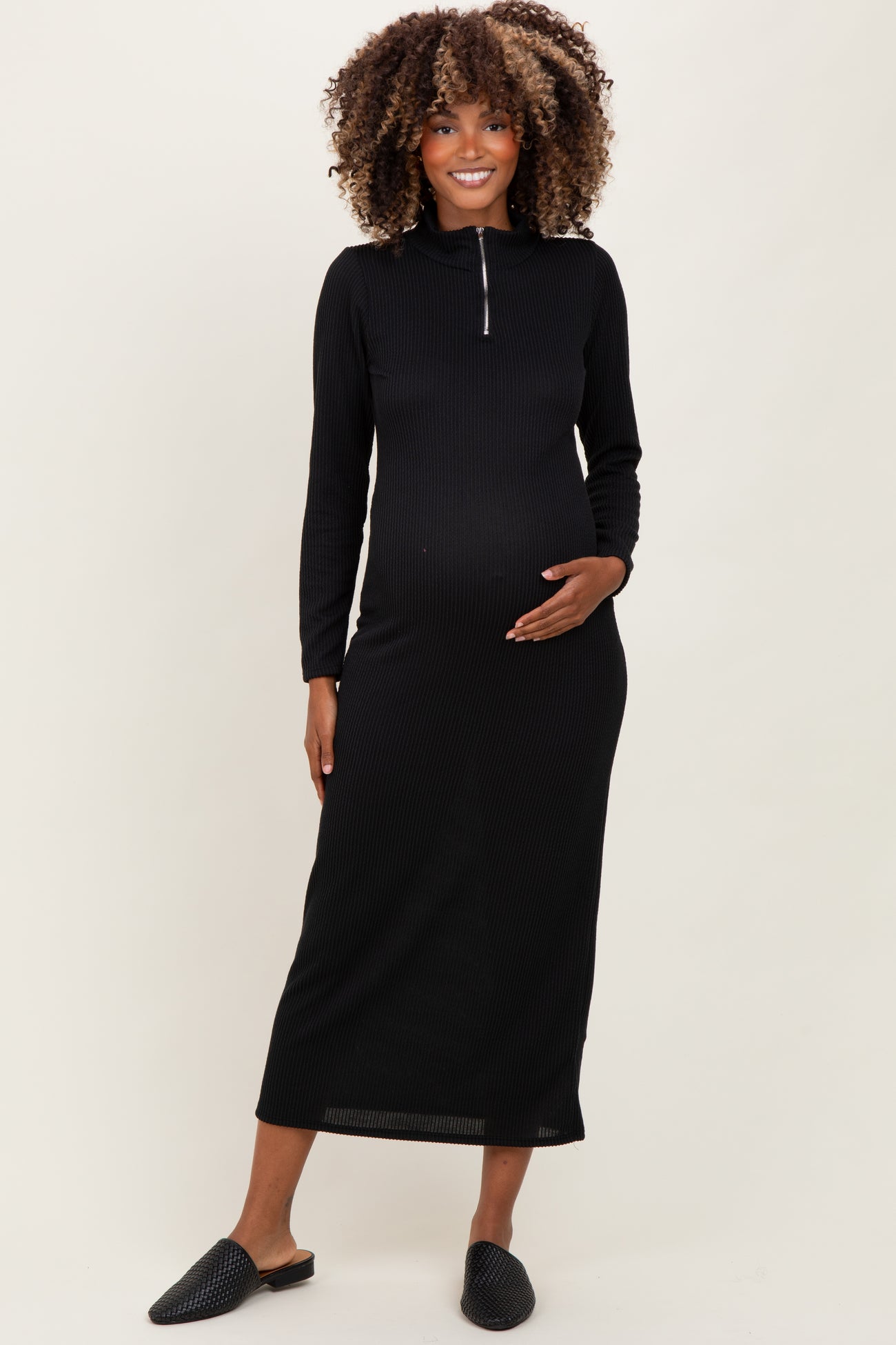 woman wearing a black ribbed maternity dress with a half zipper and a visible baby bump