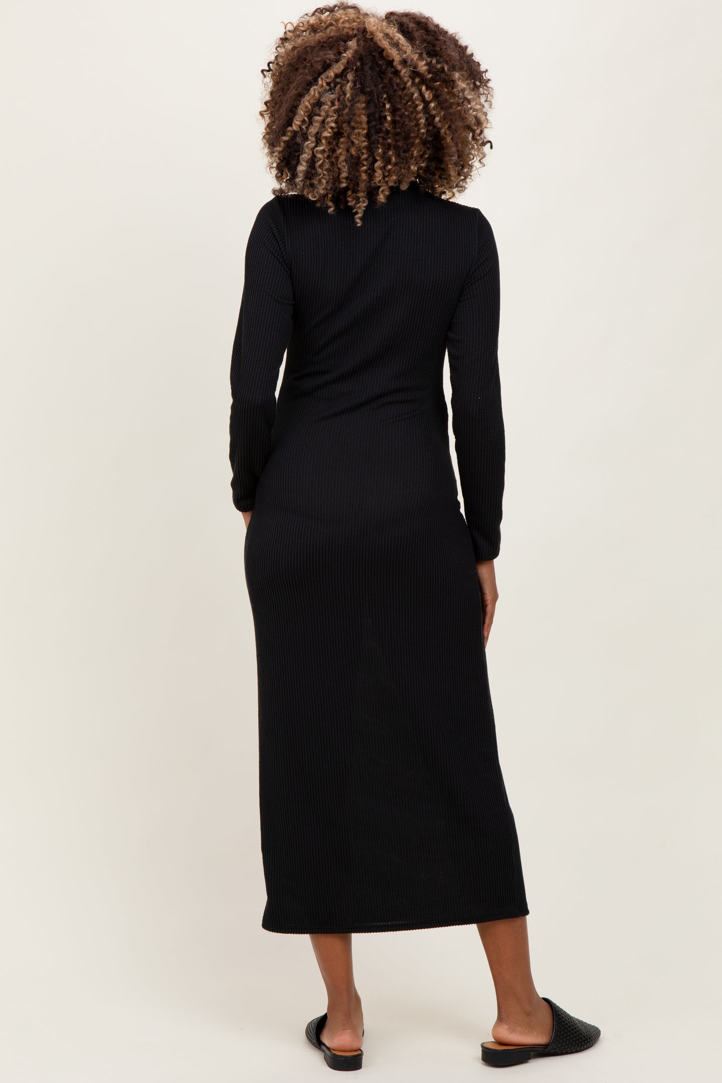 woman wearing a black long sleeve ribbed maternity dress, showing a fitted style from the back