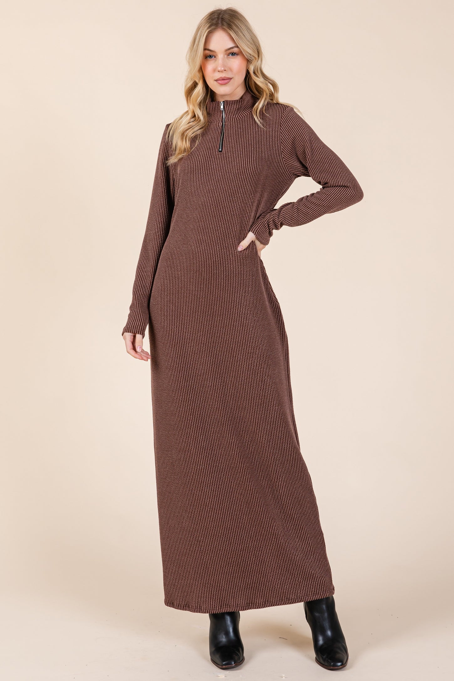 woman wearing a brown ribbed maxi dress with a zippered collar and long sleeves, paired with black ankle boots