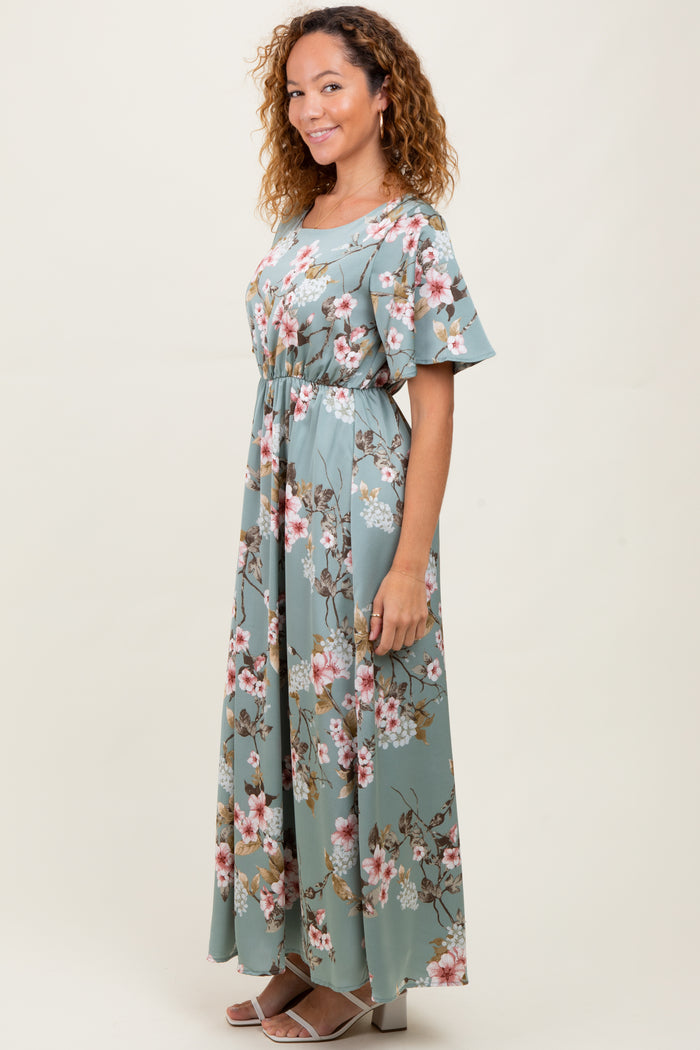 woman wearing a floral maxi dress with short sleeves and a cinched waist in a pastel green color