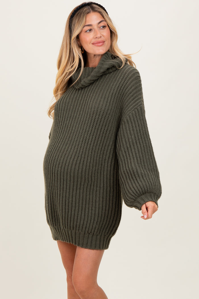 woman wearing a dark green oversized maternity sweater with a cowl neck and ribbed texture, showing her baby bump