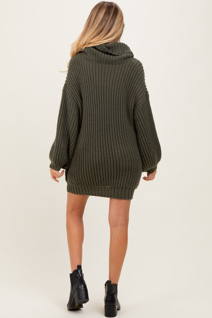 woman wearing an oversized olive green knitted maternity sweater with a cowl neck and long sleeves, facing away from the camera