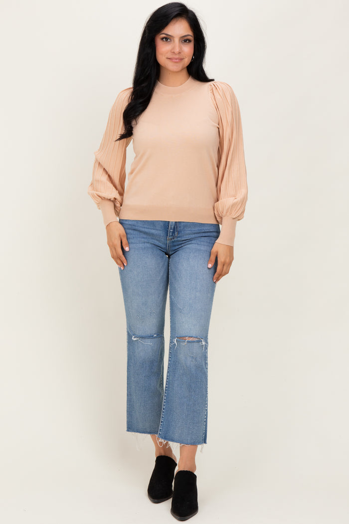 woman wearing a beige ribbed long sleeve top with puffed sleeves and blue cropped jeans with frayed hems