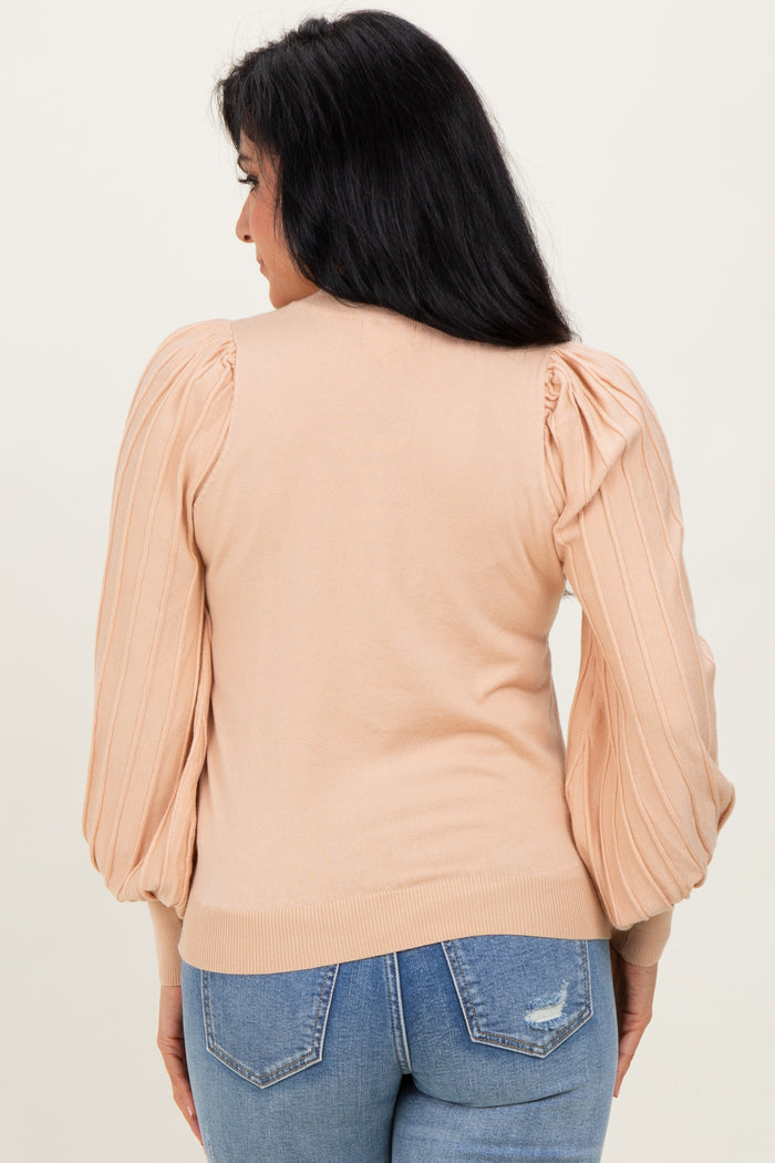 woman wearing a peach puff sleeve sweater from the back, paired with light blue jeans