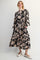 woman wearing a black floral maxi dress with long sleeves and pockets, smiling at the camera