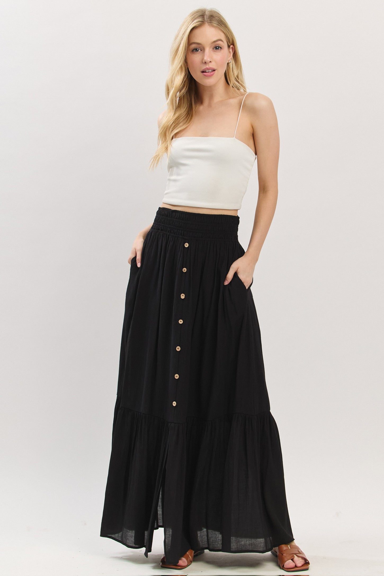 woman wearing a white ribbed crop top and a black maxi skirt with buttons and pockets