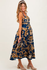 woman wearing a navy blue floral print maternity dress with spaghetti straps and a visible baby bump