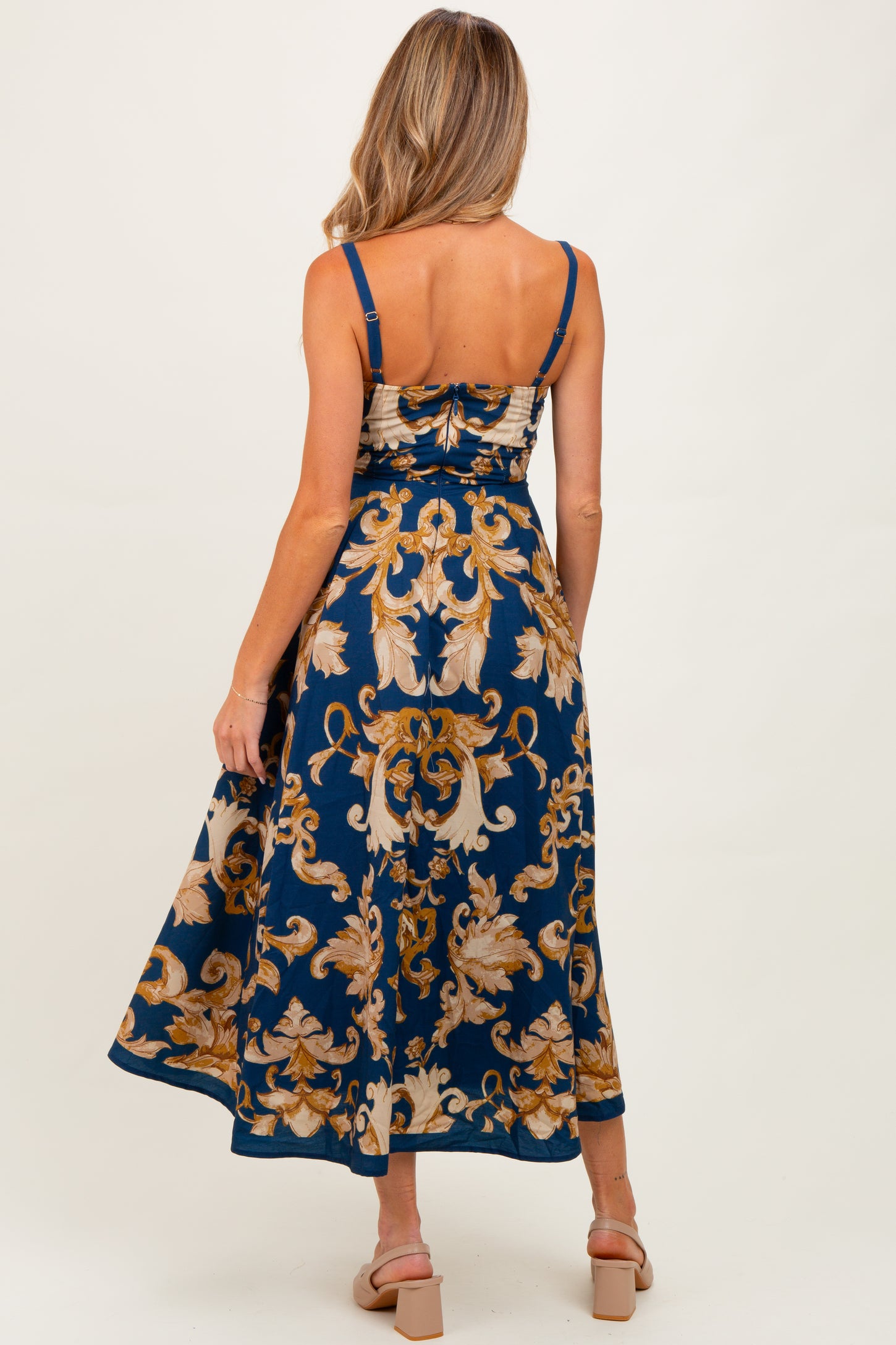 woman wearing a navy blue floral printed maternity dress with spaghetti straps and a flowy skirt
