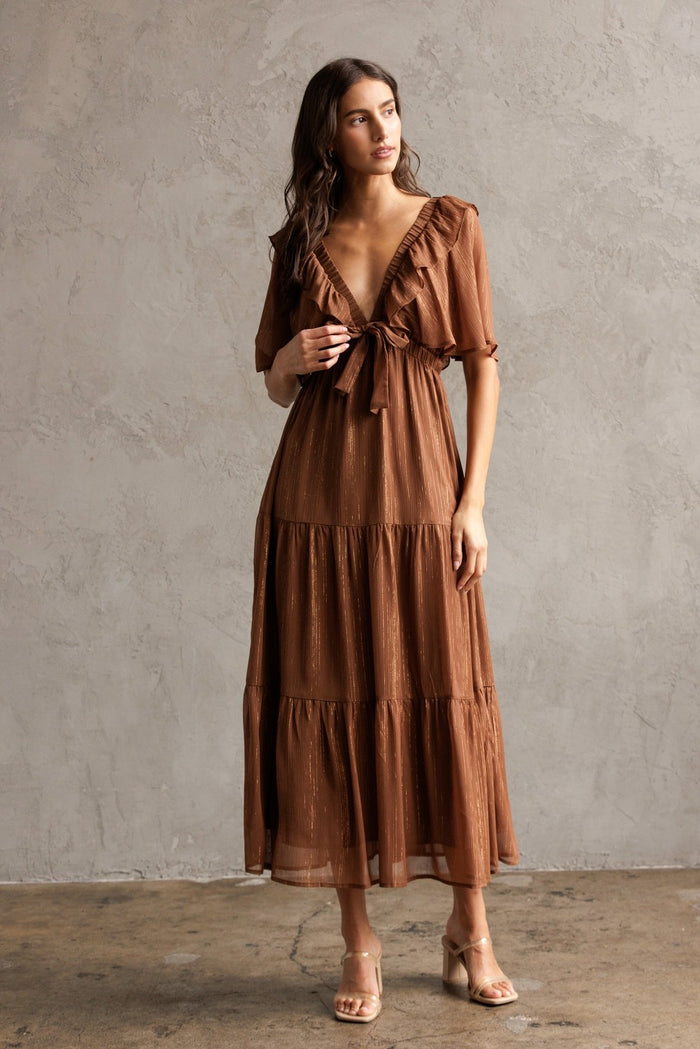 woman wearing a brown tiered maxi dress with ruffle details and a tie front neckline