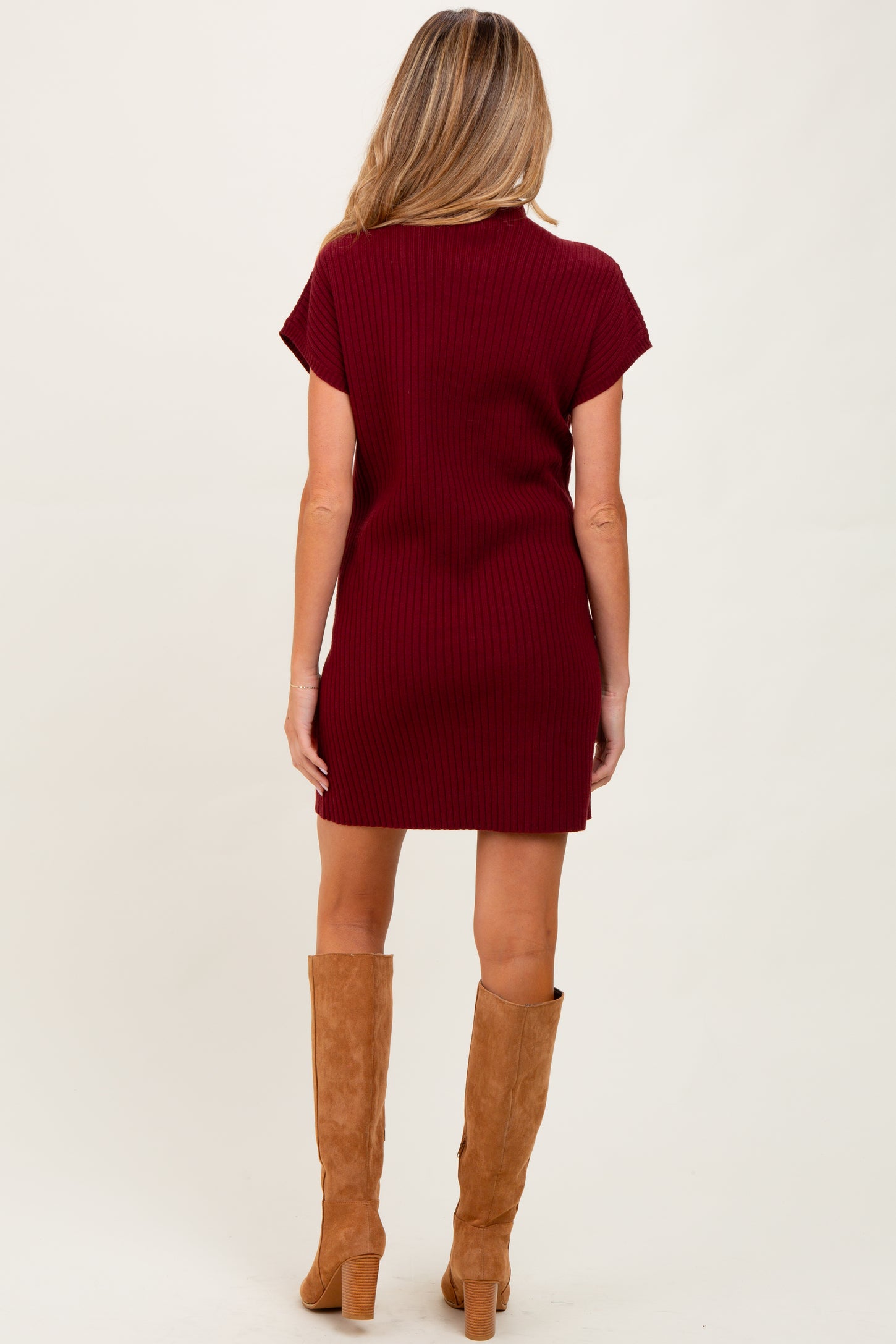 woman wearing a maroon ribbed maternity dress paired with tan knee-high boots, view from the back