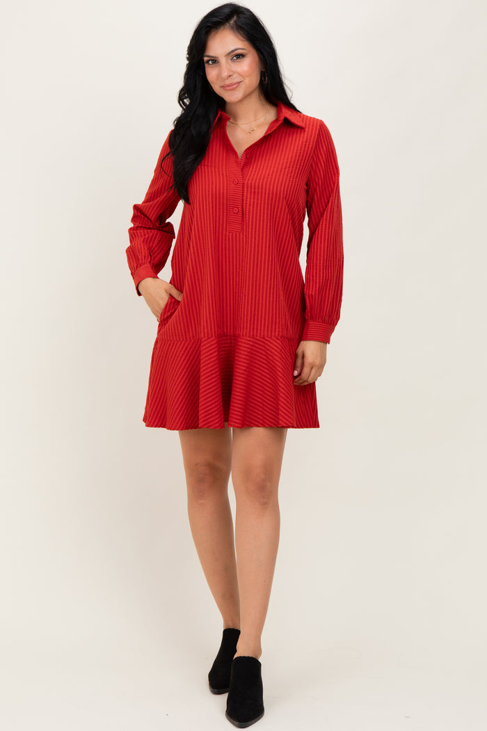 woman wearing a red striped shirt dress with long sleeves and a tiered skirt, standing confidently with hands in pockets