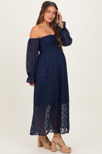 woman wearing a navy blue off-the-shoulder lace maternity dress with puff sleeves and a visible baby bump