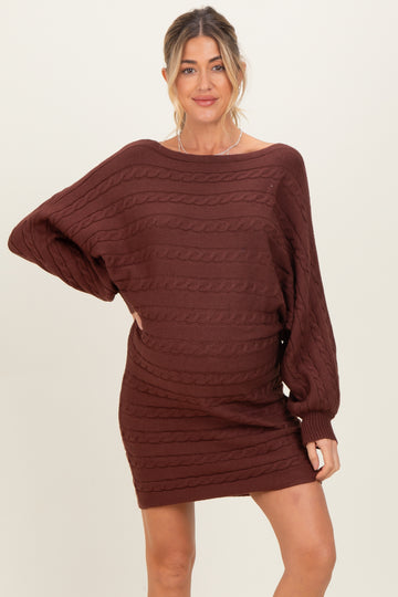 woman wearing a burgundy cable knit maternity sweater dress with oversized sleeves and a visible baby bump