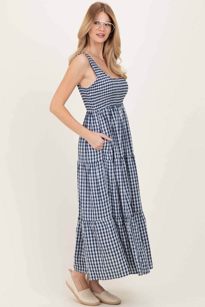 woman wearing a navy and white gingham maxi dress with adjustable straps and pockets