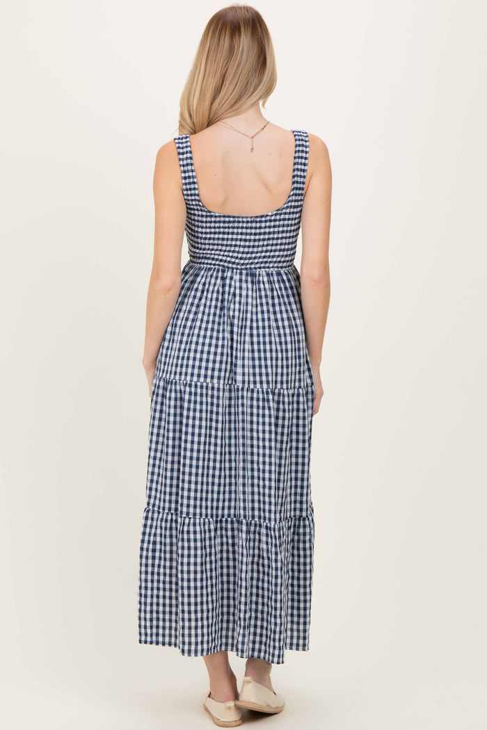 woman wearing a navy and white gingham maxi dress with a smocked bodice and tiered skirt from the back