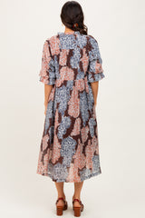 woman wearing a floral mid-length dress with ruffled sleeves and a loose fit, standing with her back to the camera