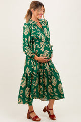 woman wearing a green floral maternity dress and holding her baby bump