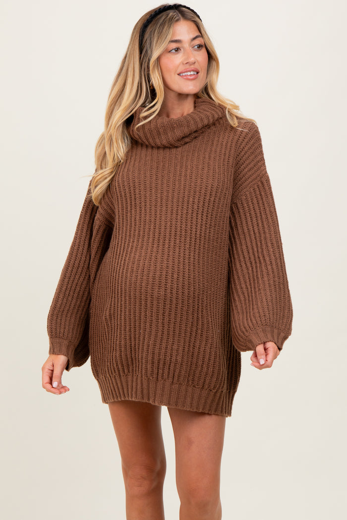 woman wearing a brown chunky knit maternity sweater with a cowl neck and oversized sleeves, showcasing a baby bump