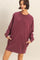 woman wearing a maroon oversized sweatshirt dress with side pockets and long sleeves